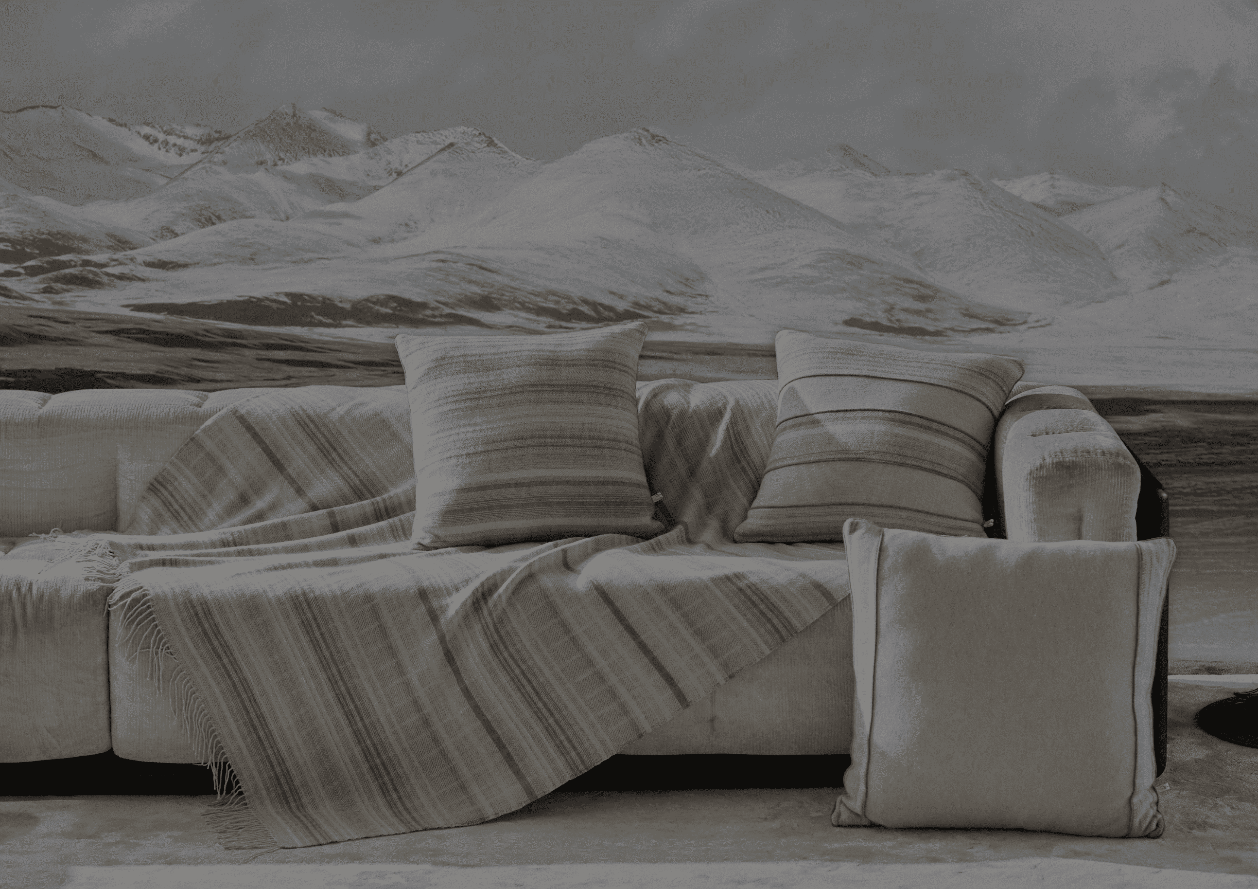 Beige sectional sofa with striped cushions against a snowy mountain backdrop