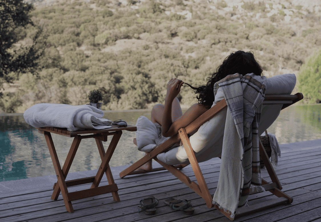 Woman sitting in a chair by a poolside with a scenic view