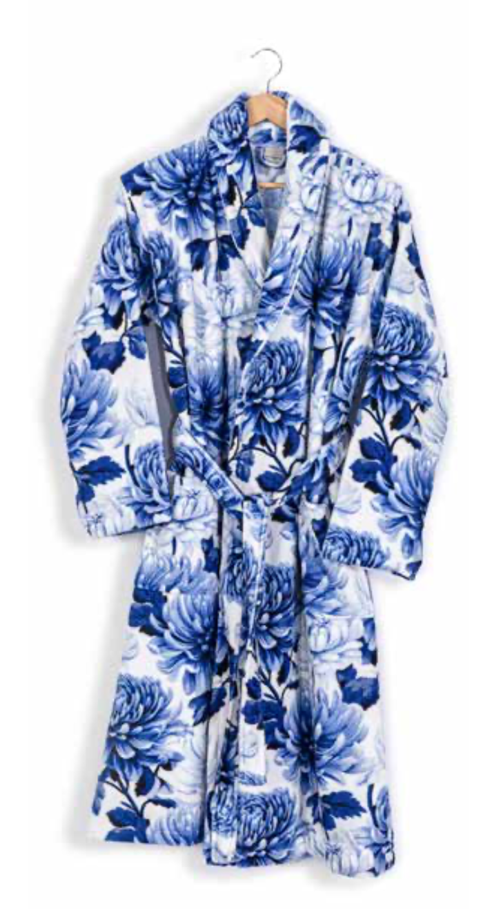 Elegant white bathrobe with bold blue floral print hanging on wooden hanger — artistic sustainable home textile design.