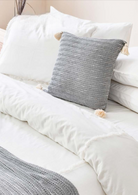 Fresco decorative cushion with textured grey weave and corner tassels — artisanal accent pillow for elegant bedding decor.