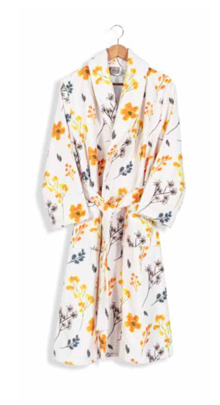 White bathrobe with delicate yellow and gray floral pattern hanging on wooden hanger — soft eco-luxury home textile design.