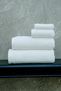 Stack of white towels on a black surface with a textured gray wall background