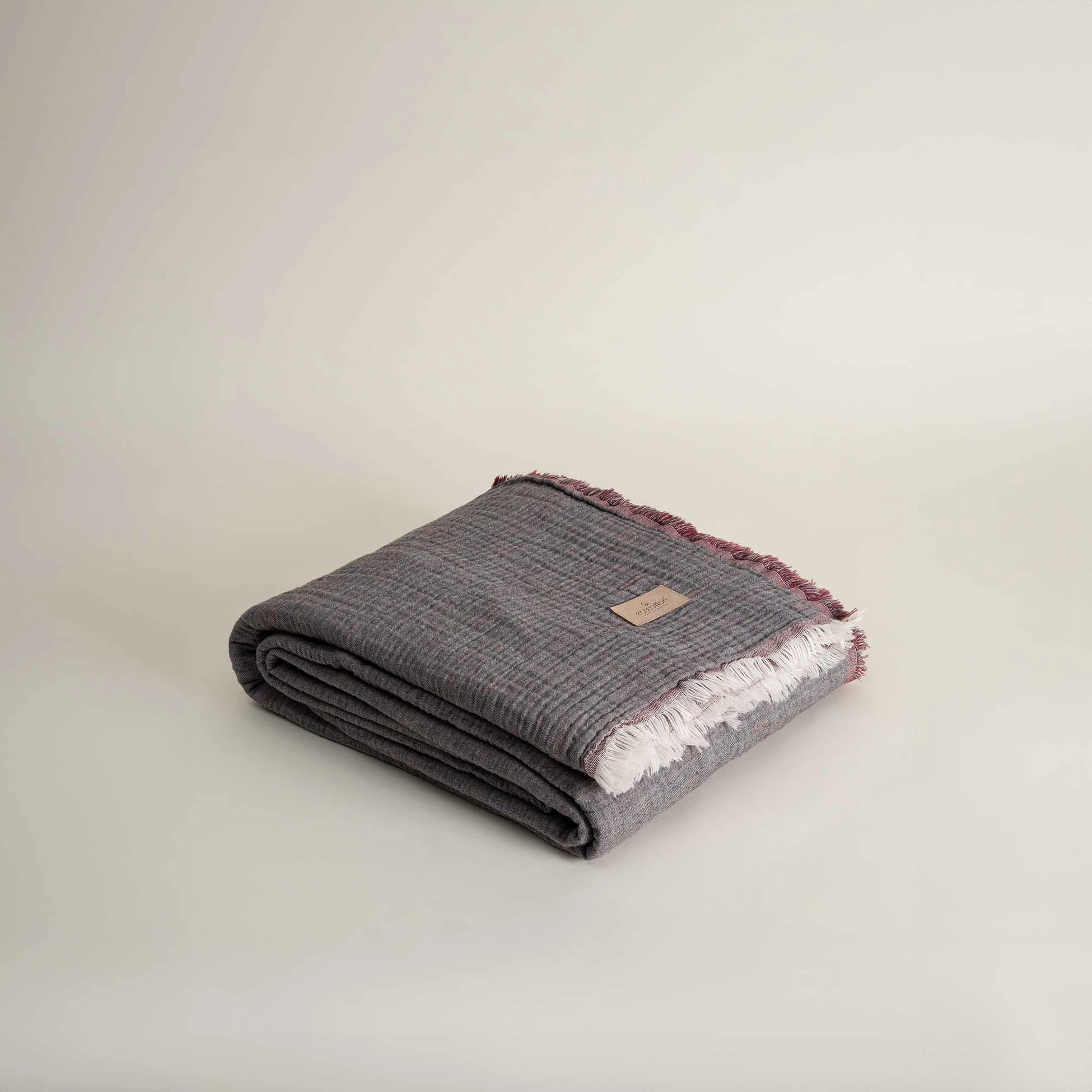 Folded reversible Muna organic gauze bed spread in Terra, neat folds, soft texture, earthy tone with organic cotton sheets.