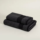 Two folded dark gray towels on a light beige background