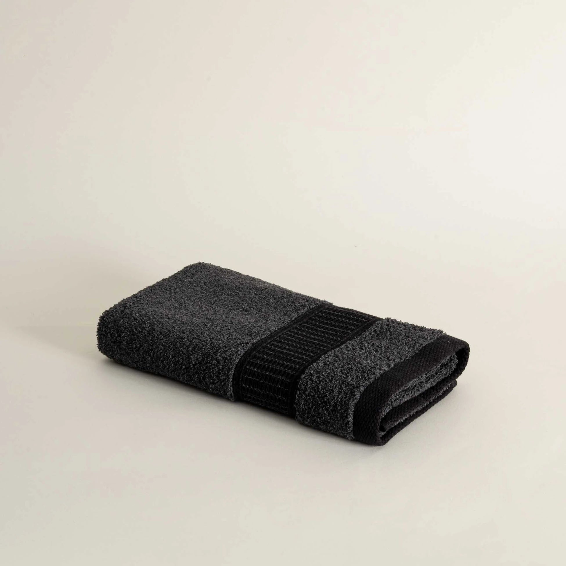 Folded dark gray towel on a beige background