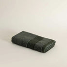 Folded dark green towel on a light beige background