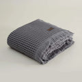 Folded gray textured towel with a brand label on a light beige background