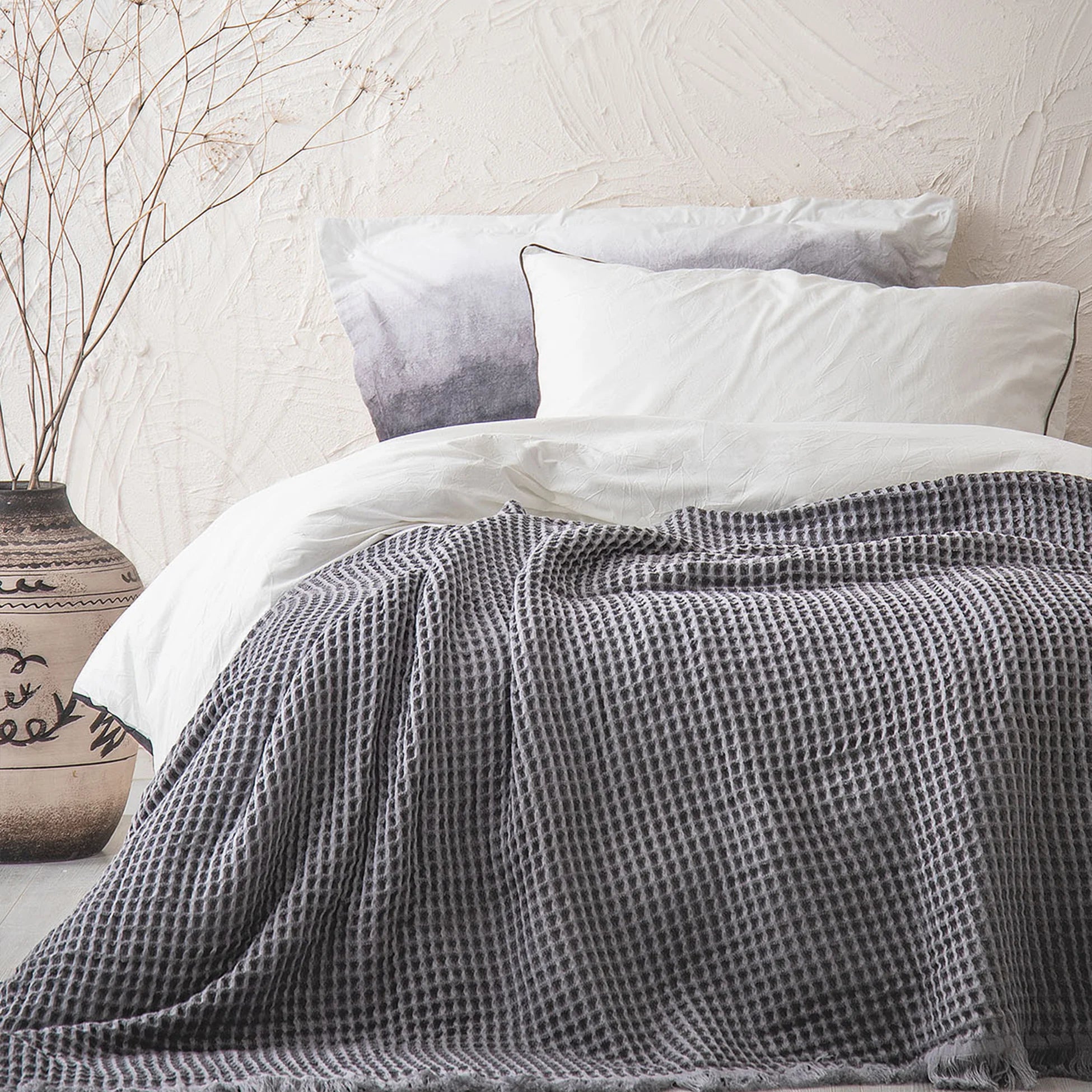 Organic Aegean Seren Waffle Large Throw 400g in Silver Suede on white bed, soft luxurious texture with organic cotton sheets.
